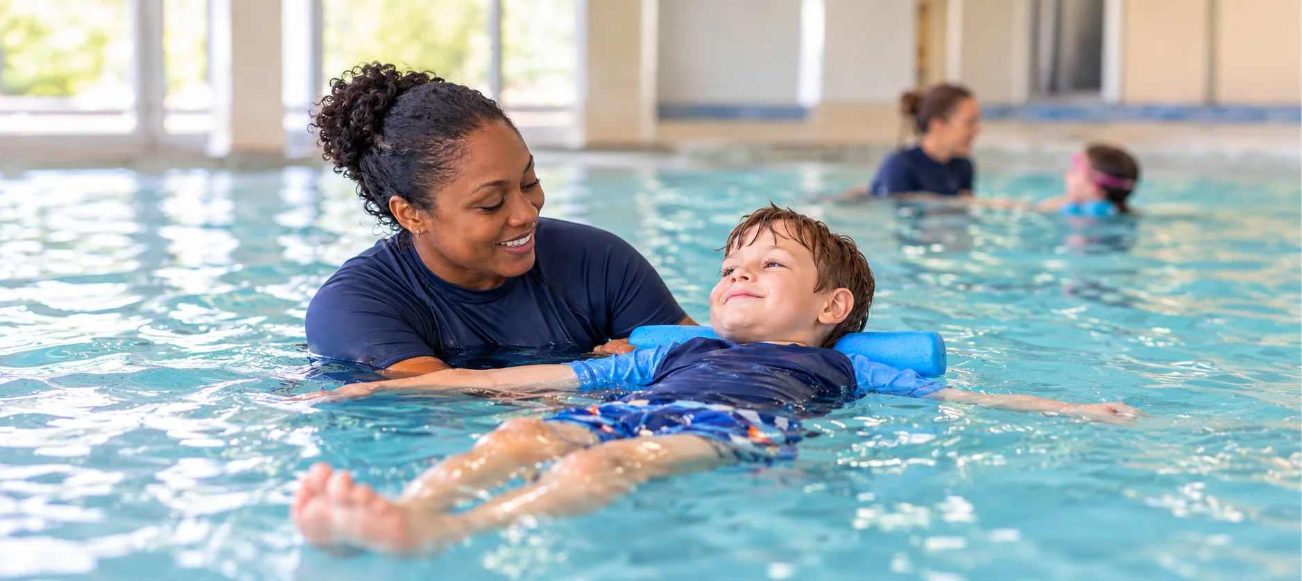 Swimming teacher supporting a child learning to float